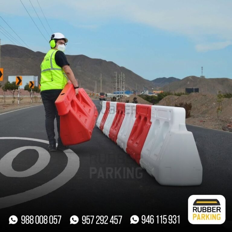 Trabajador instalando barreras viales New Jersey rojas y blancas en una carretera